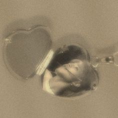 a woman is smiling in the reflection of a heart shaped mirror