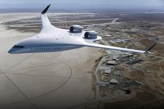 an airplane is flying in the sky over a town and desert area with buildings on either side