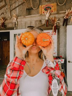 a woman holding two pumpkins in front of her eyes