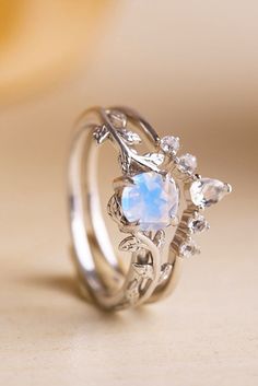 a ring with an opal stone and leaves on the side, sitting on top of a table