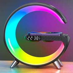 an alarm clock sitting on top of a wooden table next to a neon colored light