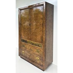 an old wooden cabinet with brass handles and drawers on the front, sitting against a white wall