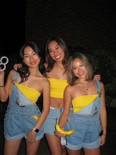 three young women standing next to each other wearing overalls and holding scissors in their hands