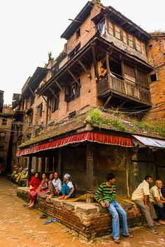 several people sitting outside an old brick building