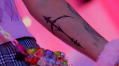 a close up of a person's arm with a tattoo on it and beads around the wrist