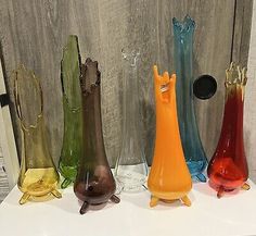 five different colored glass vases sitting on top of a white countertop next to each other