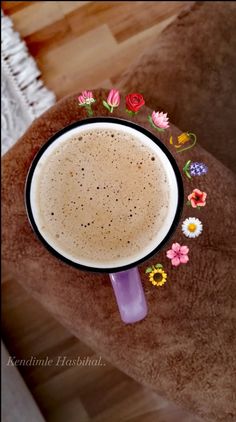 a cup of coffee sitting on top of a wooden table next to a flower arrangement