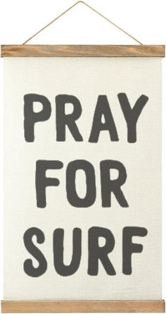 a sign that says pray for surf hanging on a wall with a wooden hanger