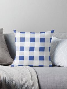 a blue and white checkered pillow sitting on top of a gray couch next to pillows