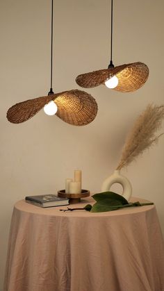 three lights hanging from the ceiling above a table with a vase and candle on it