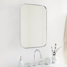 a bathroom sink with a mirror above it and two white vases on the counter