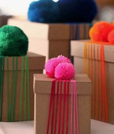 three boxes with different colored pom poms on them