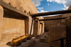 three yellow vases are sitting on the ground in front of an adobe - style building