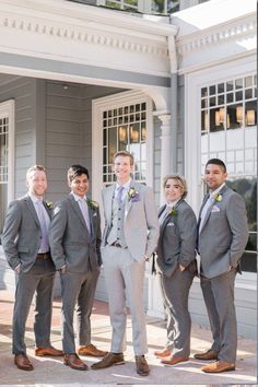 a group of men standing next to each other in front of a gray and white building