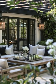 an outdoor living area with couches, tables and flowers in vases on the coffee table