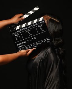 a woman is holding a clapper over her face while another person holds it up