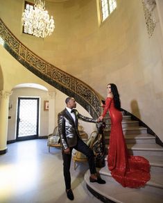 a woman in a red dress standing next to a man in a tuxedo