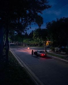 a car parked on the side of a road at night with people standing next to it