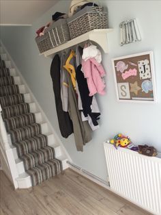 a bunch of clothes are hanging on the wall next to some stairs and a radiator