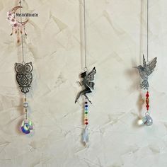 three necklaces hanging on a white wall with an owl, bird and crystal bead charm