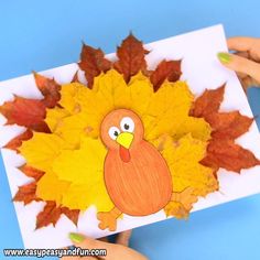 someone holding up a paper turkey with leaves on it