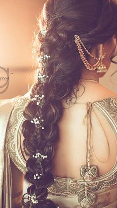 a woman with long hair wearing a gold and white sari, braided in pearls