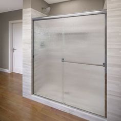 an empty room with wood floors and a shower door on the wall in front of it