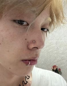 a close up of a person with freckles on her nose and piercings