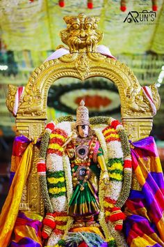 an idol is displayed in the middle of a stage with colorful cloths on it