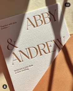 two wedding cards sitting next to each other on top of a white and orange table