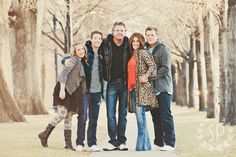 a group of people standing next to each other on a sidewalk in front of trees