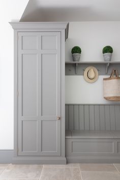 a white and grey entryway with two gray doors, a hat hanging on the wall and some potted plants next to it