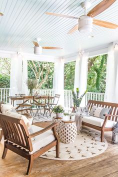 the porch is covered with white curtains and wooden furniture, along with potted plants