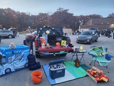 there are many picnics and coolers in the parking lot with cars parked nearby