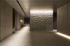 an empty room with stone walls and lights on either side of the wall is lit by recessed lighting