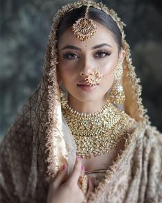 a woman in a bridal outfit with jewelry on her face and nose is posing for the camera