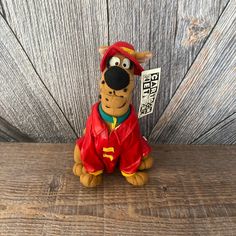 a stuffed animal that is sitting on a wooden floor with a sign in its mouth