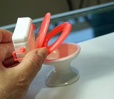 a person is holding some plastic scissors in a cup on a table with other items