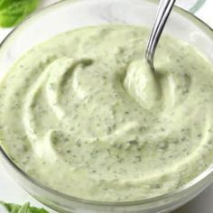 a glass bowl filled with green dip next to lettuce