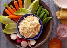 a plate with carrots, celery, and dip on it next to other food items