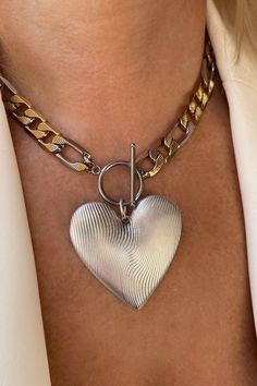 An oversized silver heart pendant hangs from a bold statement figaro link chain with a toggle clasp closure! Metal Heart Necklace With Chunky Chain, Chunky Chain Heart Metal Necklace, Chunky Heart Pendant Metal Chain Necklace, Chunky Heart Pendant Chain Necklace In Metal, Chunky Chain Heart Pendant Necklace, Heart-shaped Metal Toggle Necklace With Adjustable Chain, Metal Heart Pendant Necklace With Toggle Clasp, Vintage Metal Chain Necklace With Heart Charm, Metal Heart Toggle Necklace With Heart Charm