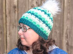 a woman with glasses wearing a green and white knitted hat