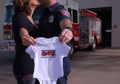 a man and woman kissing each other in front of a firetruck with a shirt on it