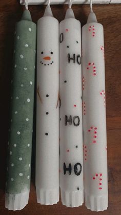 four snowman candles are lined up next to each other