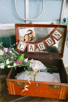 an open suitcase with some flowers and cards in the inside, sitting on a table