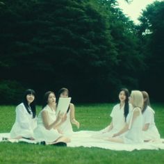 four young women sitting on a blanket in the grass