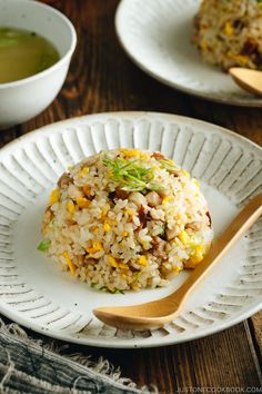 a plate with rice and vegetables on it next to a bowl of soup or tea