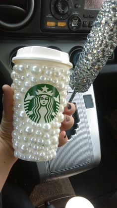 a person is holding a starbucks cup with pearls on it