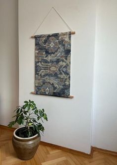 a potted plant sitting in front of a wall hanging on the side of a wall