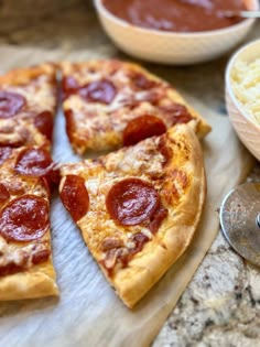 a pepperoni pizza cut into slices on a cutting board next to bowls of macaroni and cheese